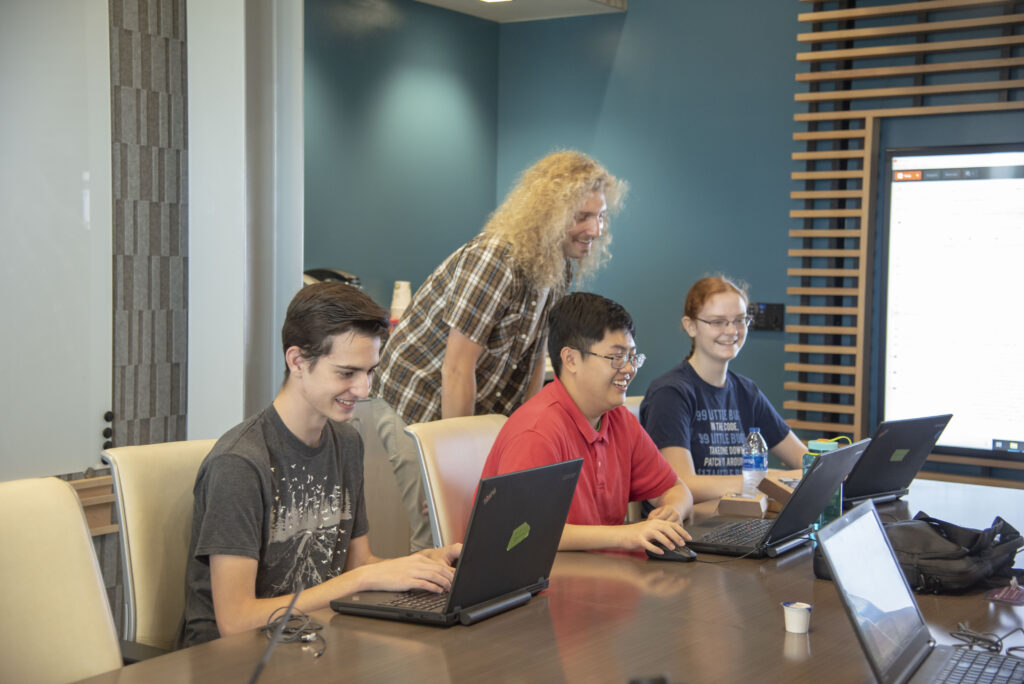 Students smiling while working on laptops.