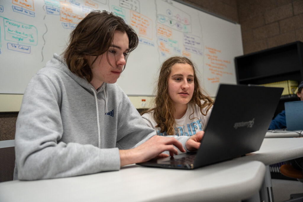 Two students working on laptop