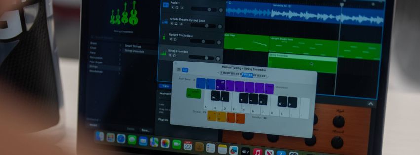 A close-up of a laptop screen displaying music software with audio tracks and a musical typing keyboard interface.