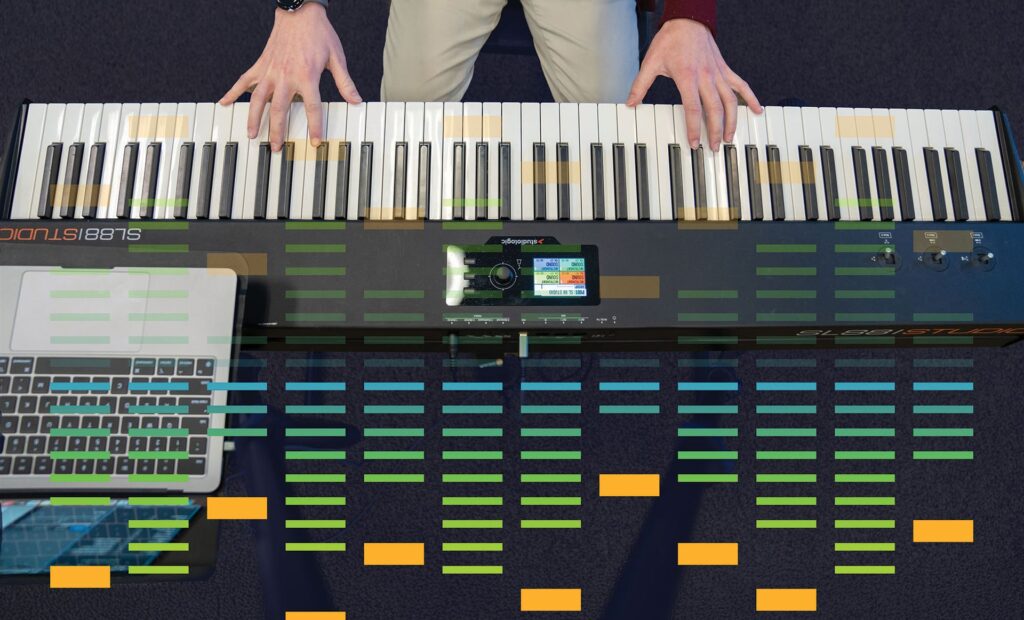 Aerial view of a person playing a keyboard, with colorful visual indicators over the keys and a laptop nearby.